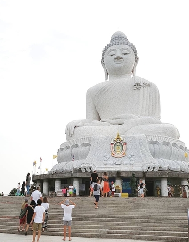 Large white Buddha statue with tourists around.
