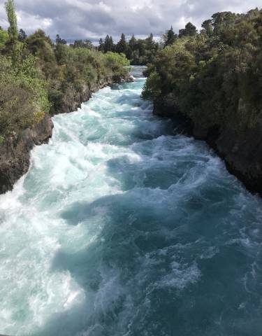 Rushing river water with rocks on a sunny day.