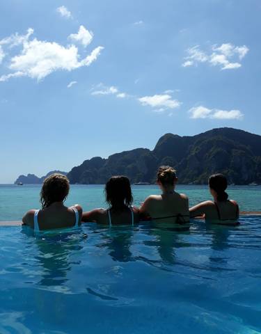 Four women in a pool overlooking a scenic bay.