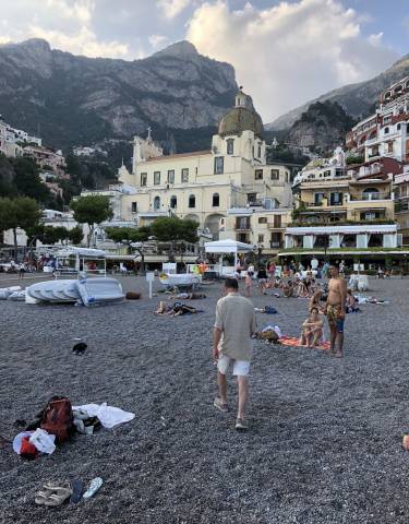 Beachfront scenery with people relaxing in front of pastel-colored buildings.