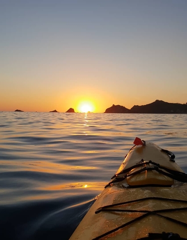 Kayak on the water at sunset with distant islands