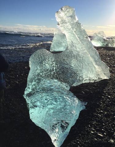 Crystal clear ice formations on a black pebble beach.