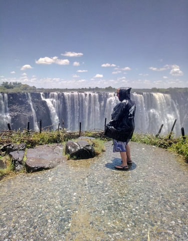 Person in a raincoat facing the majestic Victoria Falls.
