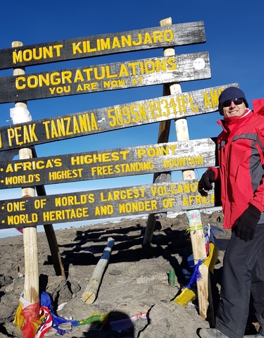Person at Uhuru Peak sign on Mount Kilimanjaro
