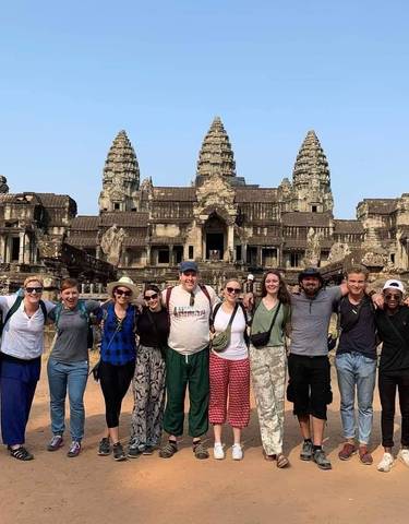 Group of tourists posing in front of Angkor Wat.