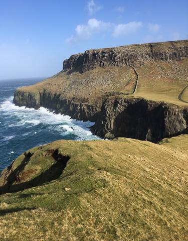 A scenic vista of a rocky coastline with waves.