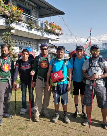 Group of hikers posing in front of a building with mountains.