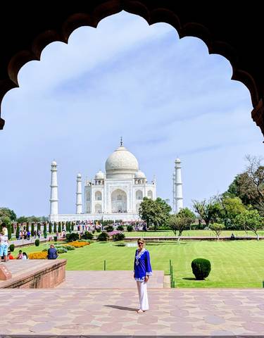 View of the Taj Mahal from an entrance archway with visitors in front.