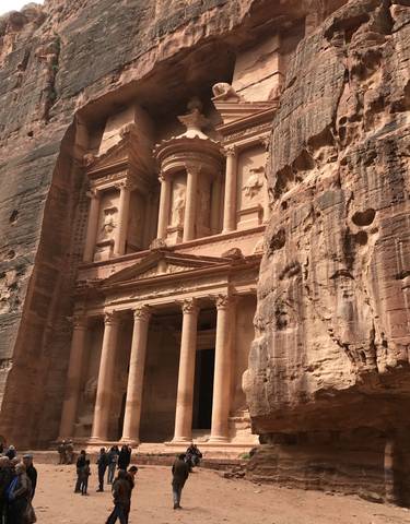 Ancient stone facade with columns carved into a canyon.