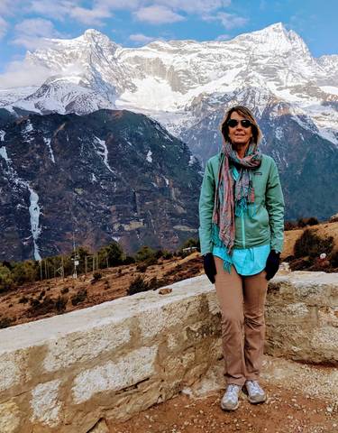 Person standing with mountains in the background wearing a scarf.