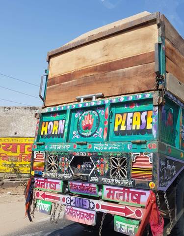 Colorful truck with intricate designs and 'Horn Please' text.