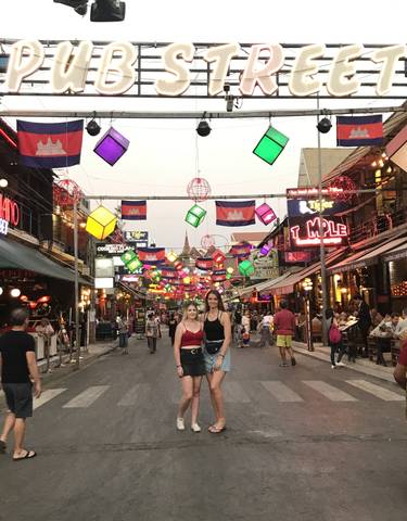 Two women posing under colorful street decorations.