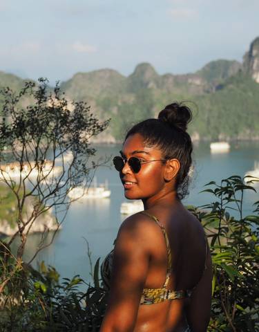 Smiling woman with sunglasses overlooking a beautiful bay.