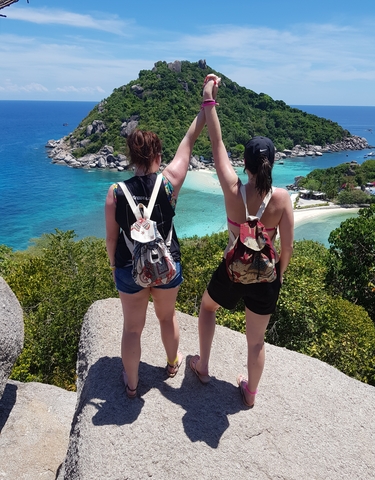 Two women viewing a scenic coastal view with clear water.
