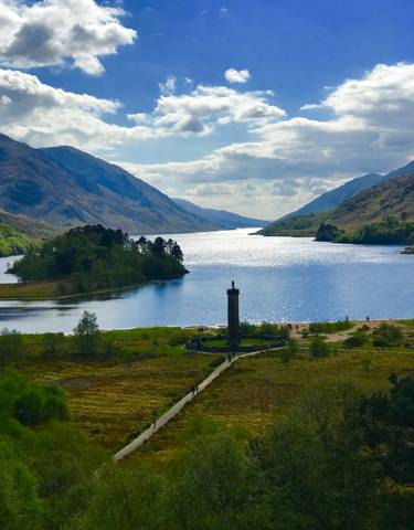 A stunning landscape of a lake surrounded by mountains under a blue sky.