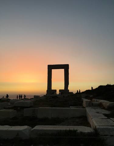 Ancient stone structure silhouetted against a colorful sunset.