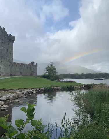 Castle with a rainbow and a lake in the foreground.