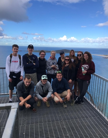 Group posing on a viewing platform overlooking the ocean