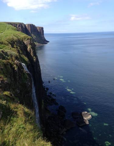 Cliffs overlooking the sea with a waterfall cascading down.