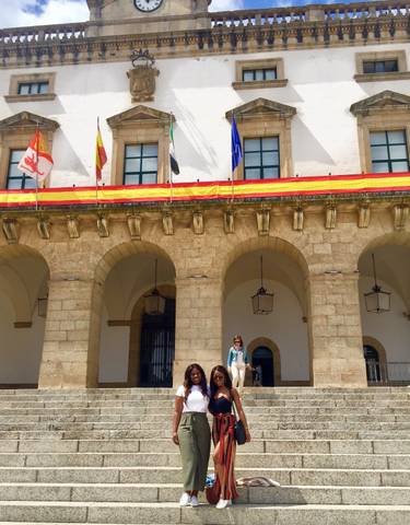Group of people in front of a building decorated with flags.