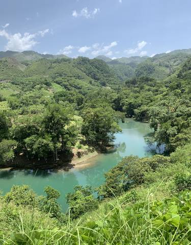 Turquoise river winding through green forested hills.