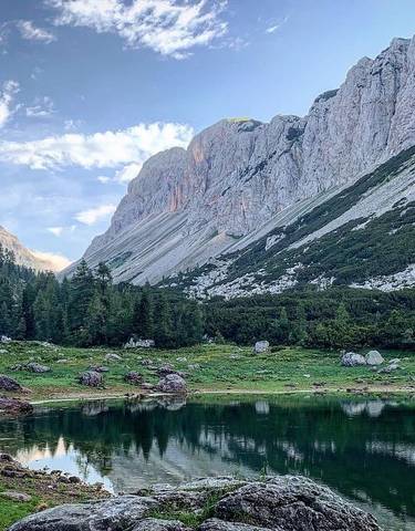 A tranquil mountain lake with a chalet and rugged peaks.
