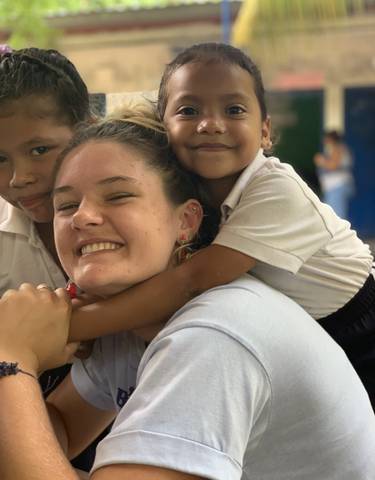 Woman smiling with two children hugging her.