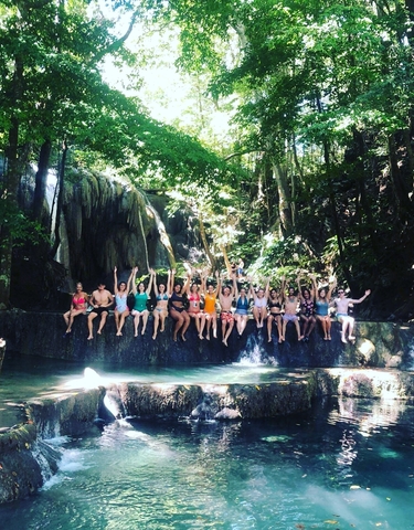 Group of people sitting at the edge of a waterfall.