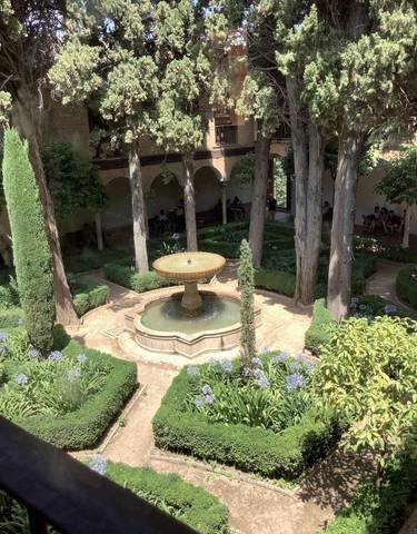 Courtyard garden with a central fountain surrounded by trees.