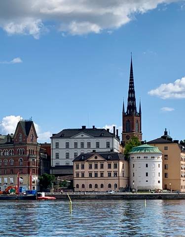 Riverfront with historic buildings and a spire.