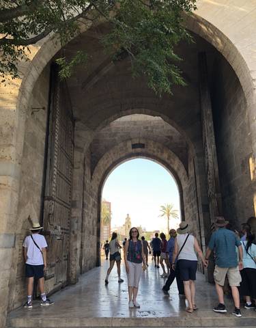 An arched entrance with people and a cityscape in the background.