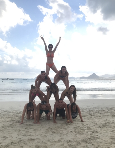 Group of people forming a human pyramid on a beach.