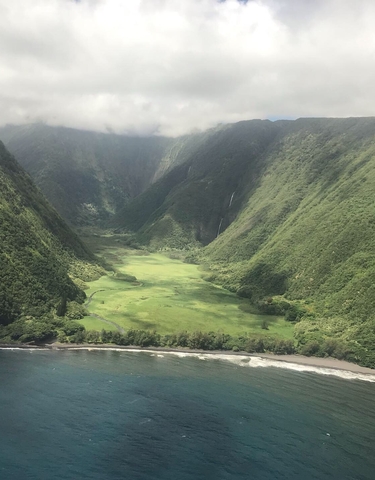 Aerial view of a lush green valley with a waterfall.