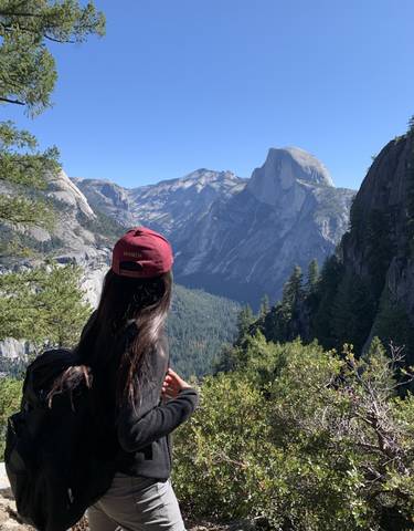 A person with a maroon cap looking at Half Dome.