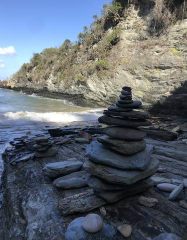 Stacked stones by a rocky shore with waves crashing.