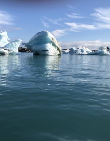 Icebergs floating in a serene lagoon with reflections on water.