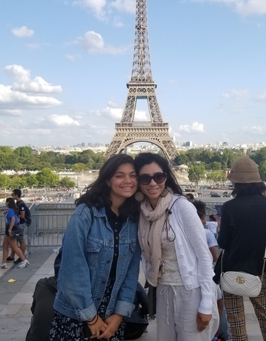 Two women smiling with the Eiffel Tower in the background.