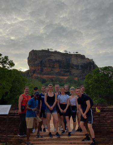 Group of tourists in front of Sigiriya rock formation.