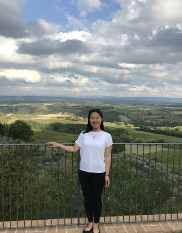 Woman posing in front of a scenic vineyard landscape.