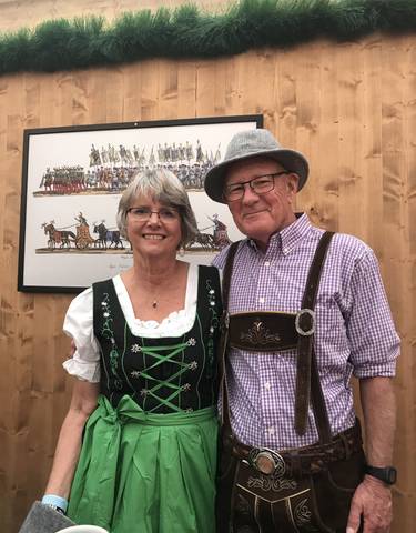 Elderly couple in traditional Bavarian clothing posing indoors.
