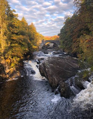 Bridge over a river with cascading waterfalls.