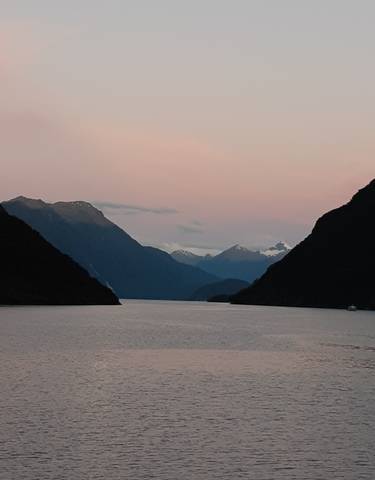 Mountainous landscape image with a body of water at dawn.