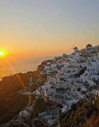 Santorini's white buildings at sunset with ocean view.