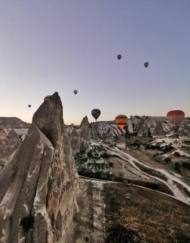 Hot air balloons floating over unique rock formations.