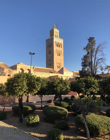 Tall tower in a courtyard with surrounding greenery.