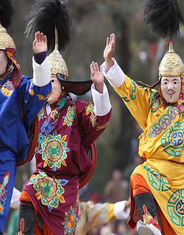 Traditional performers in colorful costumes and masks during a cultural dance.