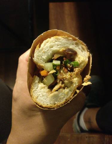 A close-up of a sandwich with vegetables and meat inside.