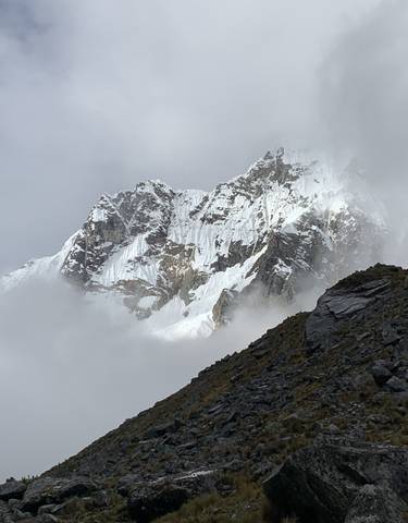 A snow-covered mountain peak seen through light clouds.