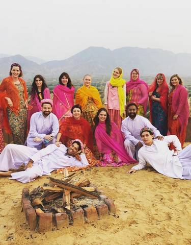 Group of people in traditional clothing posing in a desert landscape.