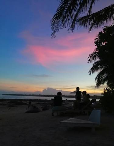 People silhouetted against a colorful sunset on the beach.